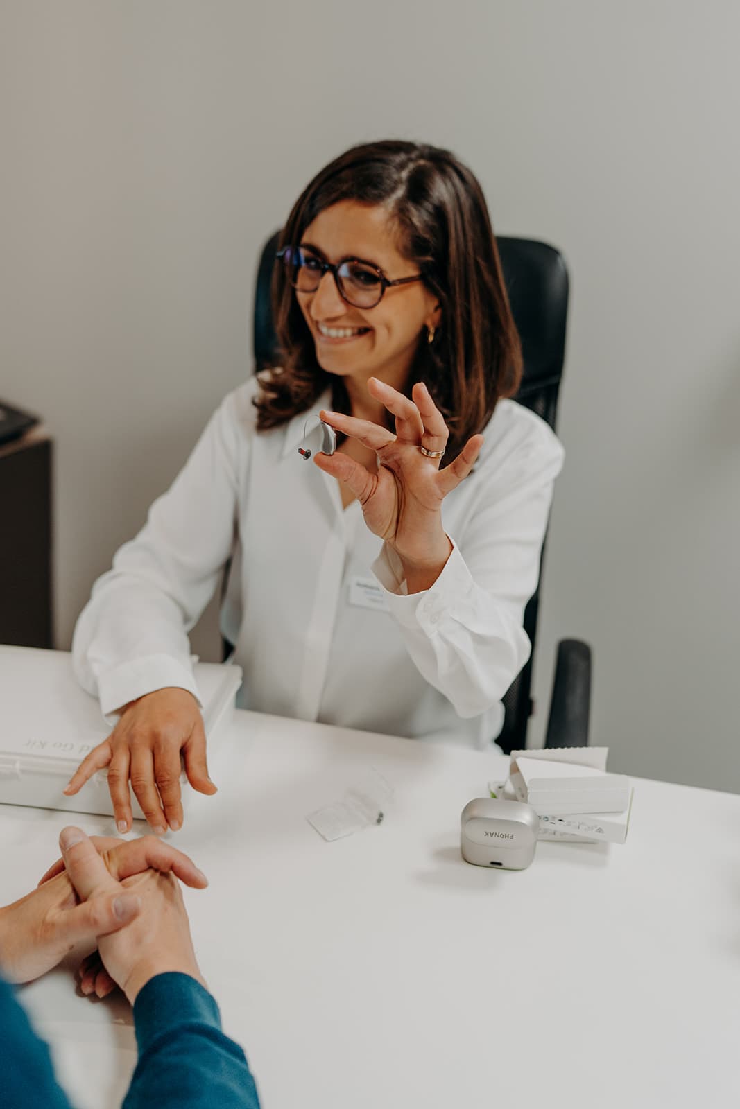 Audioprothésiste présentant un appareil auditif lors d’une consultation